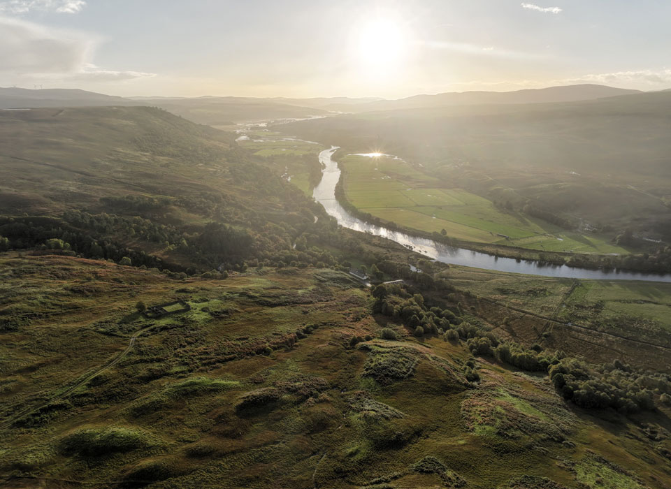 an aerial view of a river running through a forest valley